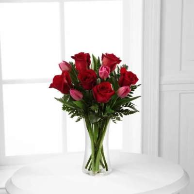 Red roses and pink tulips arranged in a clear glass vase