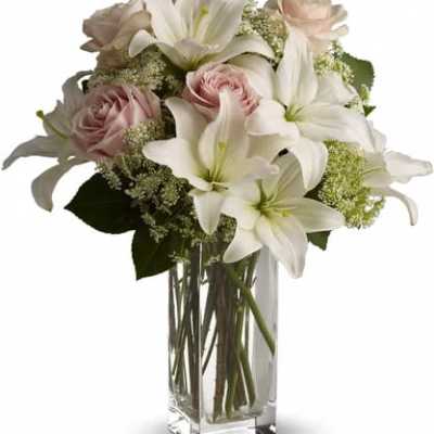 White lilies and pale pink roses in a clear glass vase