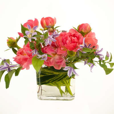 Pink flowers and purple blossoms arranged in a clear glass vase