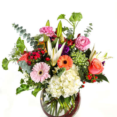 Mixed bouquet in a round glass vase with pink, white, orange, and red flowers