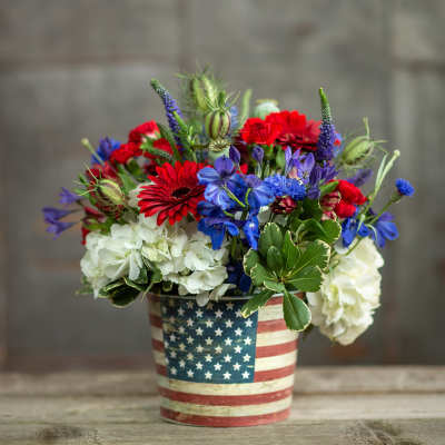 Red, blue, and white flowers in an American flag tin container
