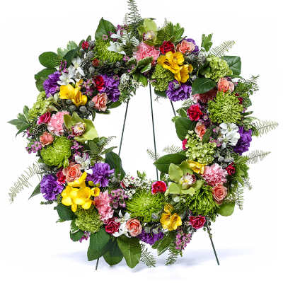 Colorful mixed flower wreath with roses, orchids, mums, and carnations on a metal stand