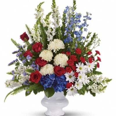 Red roses, white mums, and blue flowers in a white vase