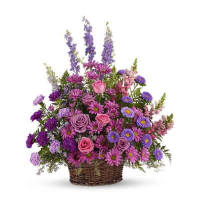 Purple and pink mixed flower arrangement in a wicker basket