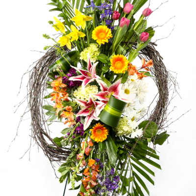 Tall floral standing spray with mixed blooms in a twig wreath frame