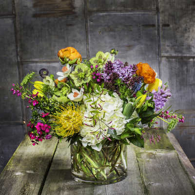 Mixed bouquet in a clear glass vase with white, yellow, orange, and purple flowers