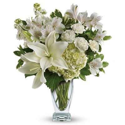 White lilies and mixed white flowers in a clear glass vase