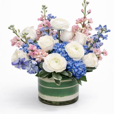 White roses and blue hydrangeas in a green striped vase
