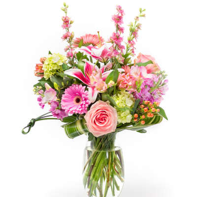 Mixed pink and peach flowers arranged in a clear glass vase