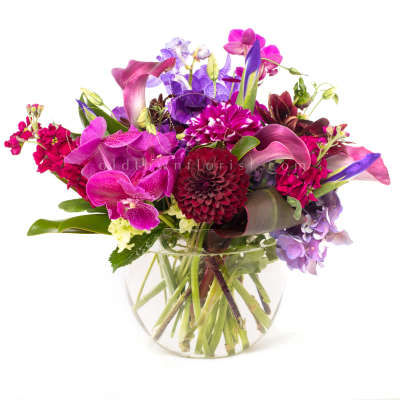 Mixed purple and pink flowers arranged in a clear glass vase