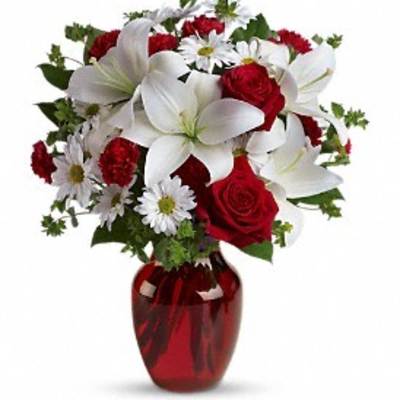 Bouquet of red roses and white lilies in a red glass vase