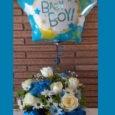 Blue baby boy balloon above a white and blue flower arrangement