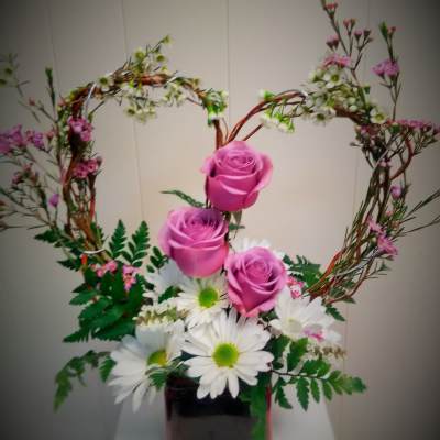 Pink roses and white daisies in a square vase with heart-shaped branches