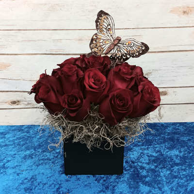 Dark red roses in a black box with a decorative butterfly topper