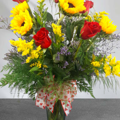 Bouquet of red roses and yellow sunflowers in a glass vase