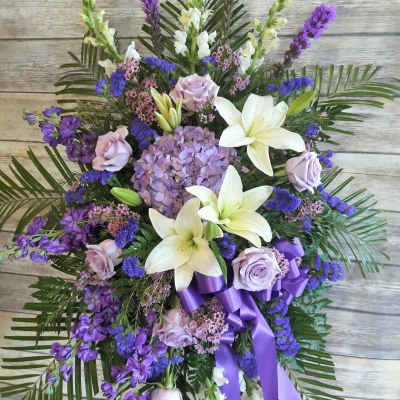 Purple and white standing spray with lilies, roses, and ribbon
