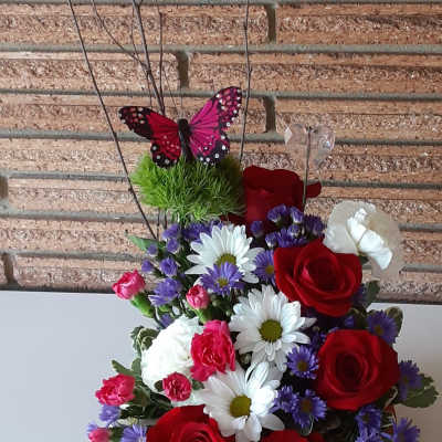 Bouquet of red roses, white daisies, and purple flowers with butterfly picks