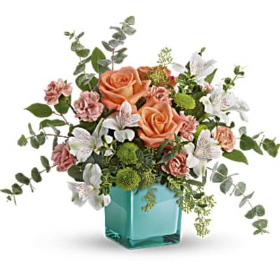 Peach roses and white lilies in a turquoise glass vase