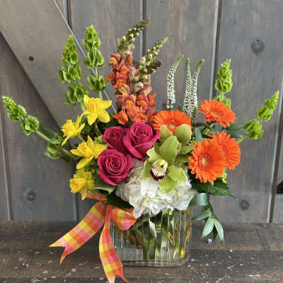 Colorful mixed bouquet in a clear glass vase with a plaid ribbon