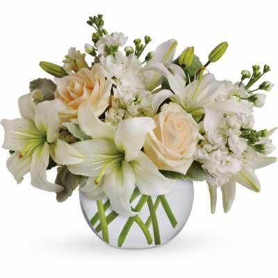 White lilies and cream roses arranged in a round glass vase