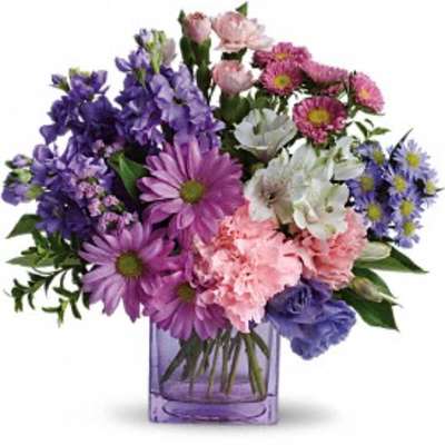 Mixed purple and pink flowers in a purple glass vase