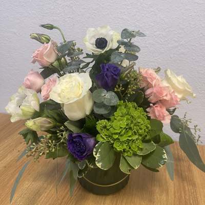 Mixed bouquet of pink, white, purple, and green flowers in a round vase