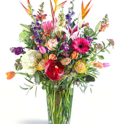 Mixed bouquet in a clear glass vase with pink, orange, purple, and white blooms
