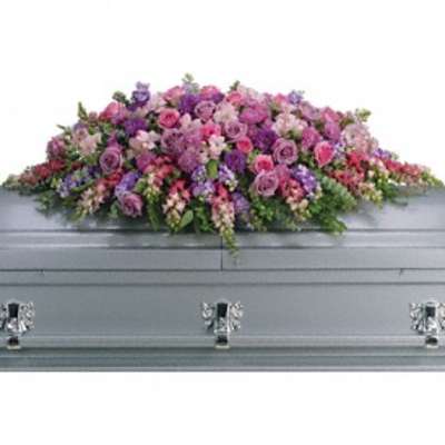 Pink and purple floral casket spray on a gray casket