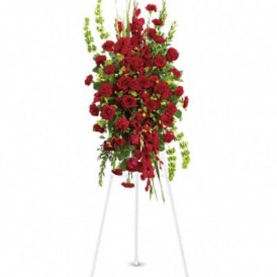 Tall standing spray of red roses on a white easel