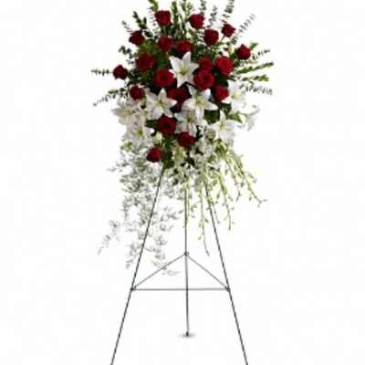 Standing floral spray with red roses and white lilies on an easel