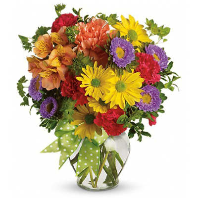 Colorful mixed bouquet in a clear glass vase with a green polka-dot ribbon