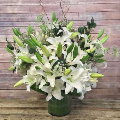 White lilies arranged in a green glass vase