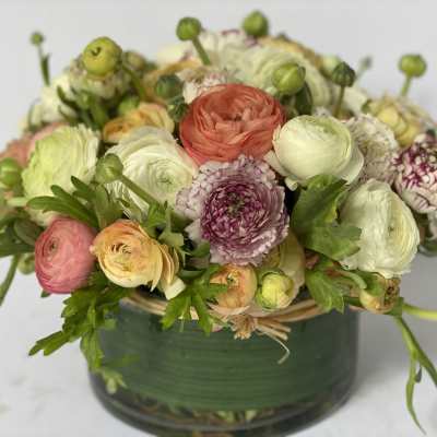 Mixed pastel flowers arranged in a low glass vase