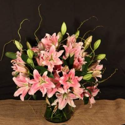 Pink lilies arranged in a glass vase with unopened buds