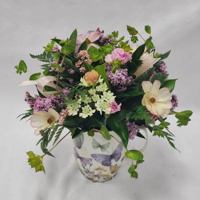Mixed pink and cream flowers in a butterfly-patterned mug vase