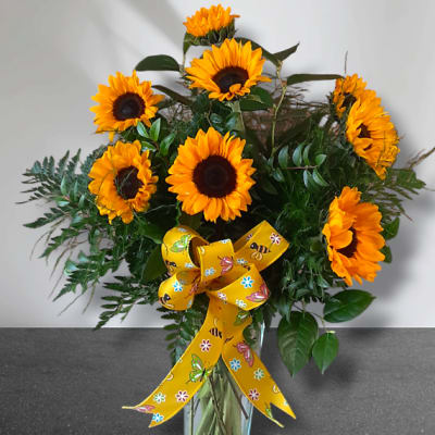 Sunflower bouquet in a glass vase with a yellow patterned ribbon