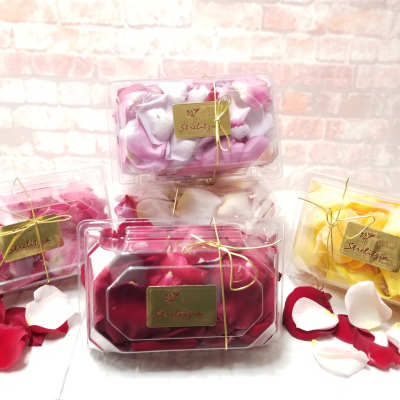 Plastic boxes filled with rose petals in pink, white, red, and yellow