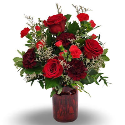 Red roses and carnations in a red glass vase