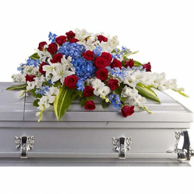Red, white, and blue casket spray with roses, lilies, and hydrangeas on a silver casket.