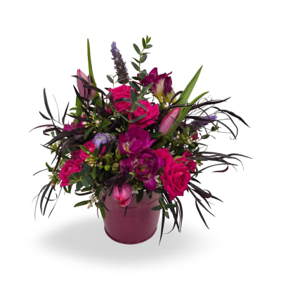 Vibrant arrangement of hot pink roses and purple flowers in a pink ceramic pot