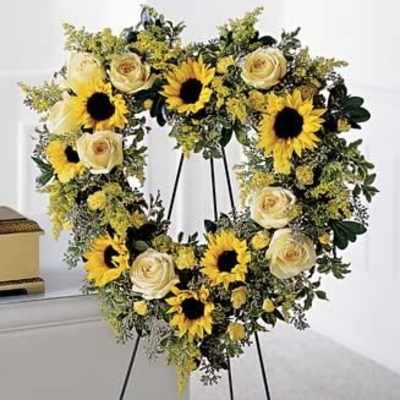Round wreath of yellow sunflowers and ivory roses on a black easel stand