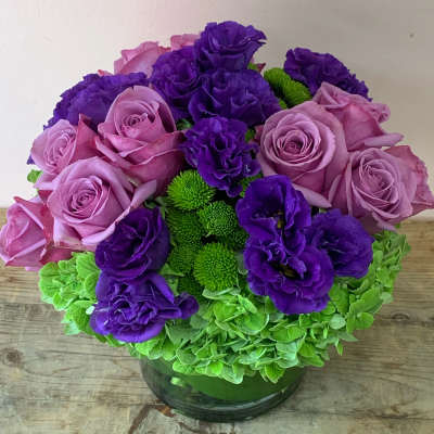 Purple and pink roses with green chrysanthemums in a glass vase