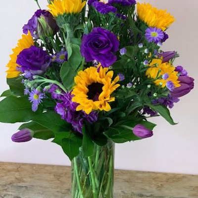 Bouquet of purple and yellow flowers in a clear glass vase