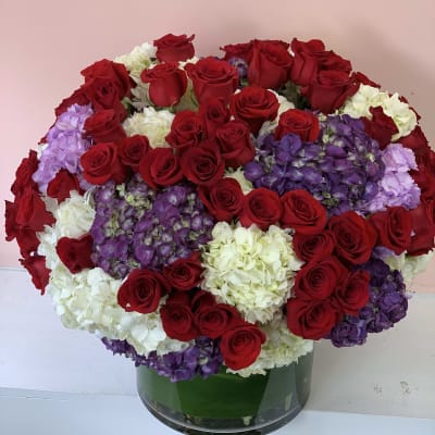 Large bouquet of red roses, white hydrangeas, and purple hydrangeas in a glass vase