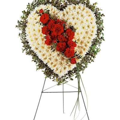Heart-shaped funeral spray of white and red flowers on a stand