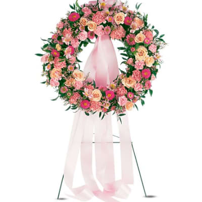Pink and peach floral wreath on a stand with a long pink ribbon