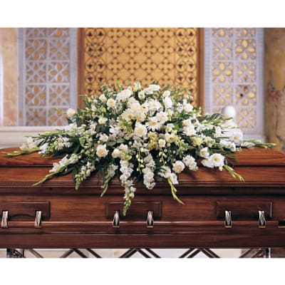 White floral casket spray on a wooden casket
