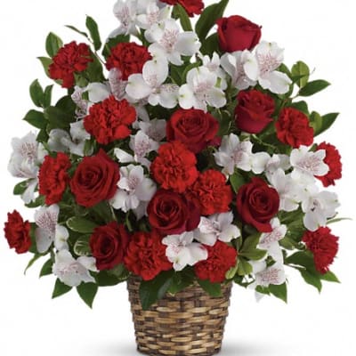 Red roses and carnations with white orchids in a woven basket