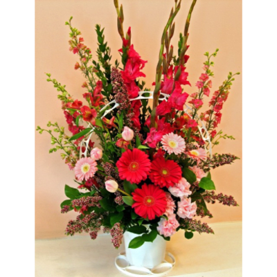 Tall red and pink flower arrangement in a white vase