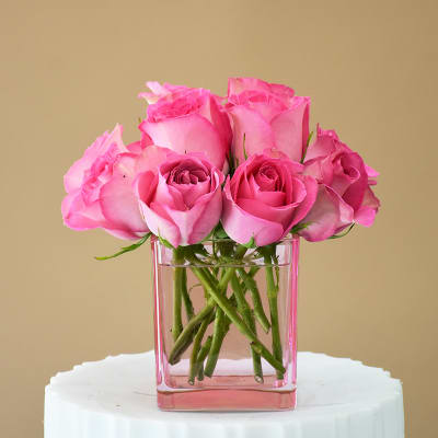 Pink roses arranged in a clear square vase